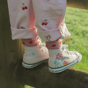 Child wearing Lamington merino crew socks in soft pink with cherry red spots made in New Zealand.