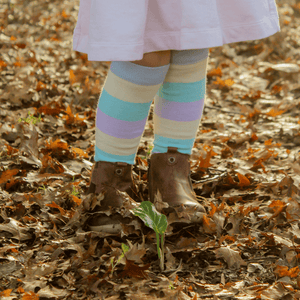 Child wearing Lamington merino knee high socks with pastel blue, yellow, green and lilac stripes made in New Zealand.