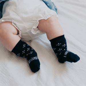 Baby wearing Lamington merino crew socks in navy with floral pattern made in New Zealand.