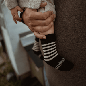 Baby wearing Lamington merino crew socks in black with latte stripes made in New Zealand.