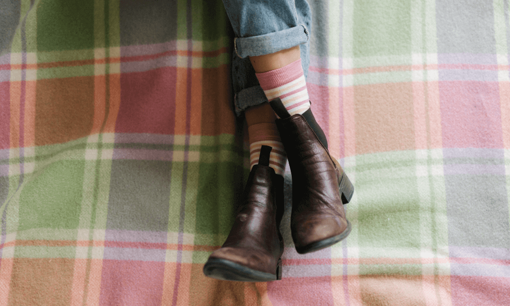  stylish boots and cosy striped socks on a plaid blanket.