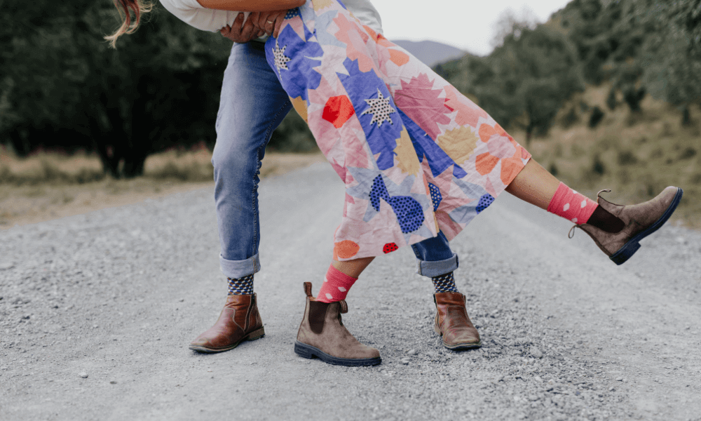 A couple dancing on a gravel road, showcasing colorful Merino socks