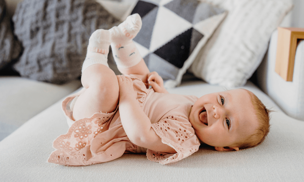 A baby wearing merino socks while playing on a couch
