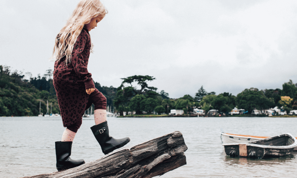 Girl walking on a log near water wearing Lamington merino socks